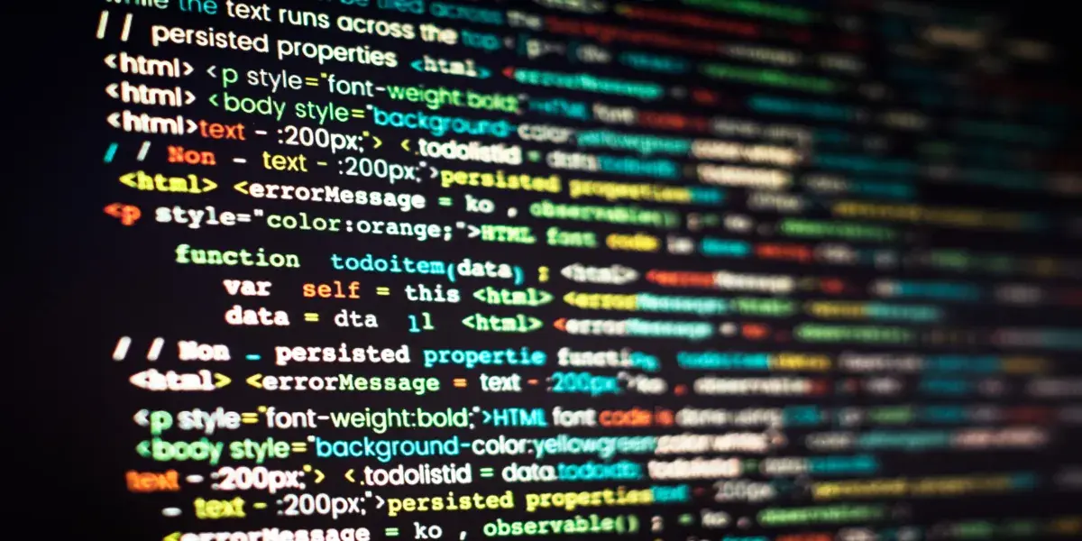 Nahaufnahme eines dunklen Bildschirms mit farblich hervorgehobenem HTML-, CSS- und JavaScript-Code zur Gestaltung einer Webanwendung.